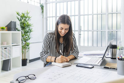 Young woman using phone while sitting on table