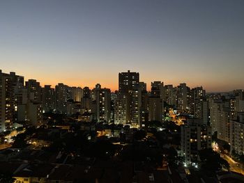 Illuminated buildings against clear sky at night