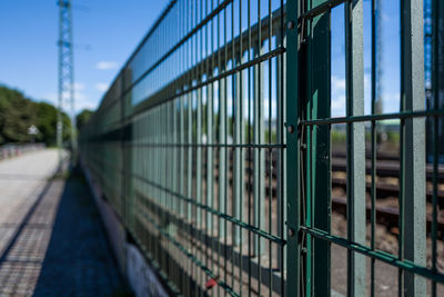 Metal fence by bridge against sky
