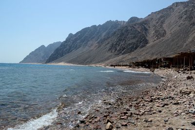 Scenic view of sea and mountains against clear sky