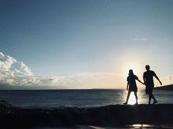 Silhouette people on beach against sky