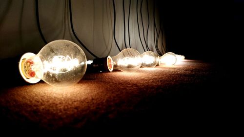 Close-up of illuminated light bulb on table