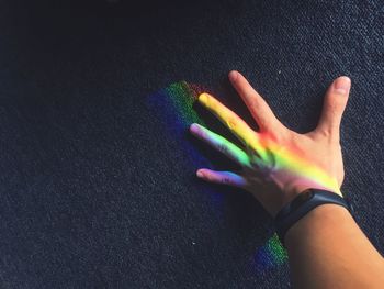 Cropped hand with colorful lights against wall