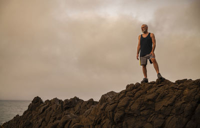 Man standing on rock against sky