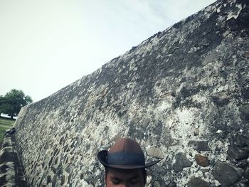 Man standing by wall against clear sky