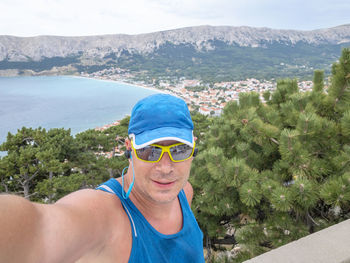 Portrait of smiling man wearing sunglasses against sea and sky