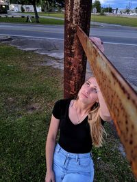 Portrait of young woman standing on tree trunk