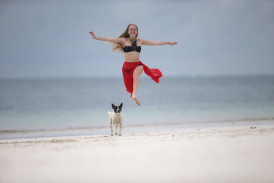 Full length of young woman jumping on beach
