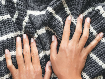 Woman's hands on gray knitted sweater with white stripes. folded warm clothing. crumpled textile