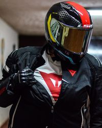 Close-up of man wearing helmet with riding gears indoors