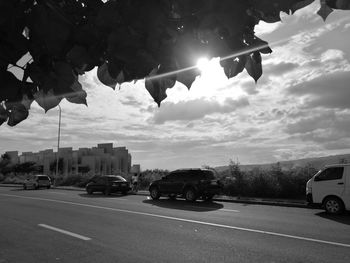 Cars on city street against sky