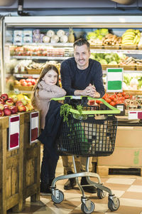 Full length portrait of father and daughter grocery shopping in supermarket