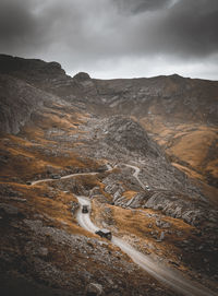 Scenic view of road by mountains against sky