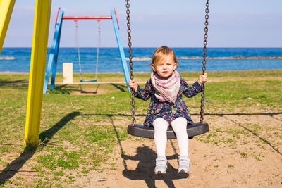 Portrait of girl sitting on swing at playground