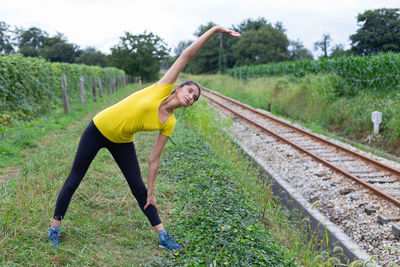 Rear view of woman exercising on railroad track