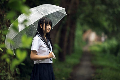 Woman holding umbrella standing during rainy season
