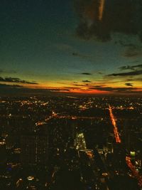 Aerial view of illuminated city buildings against sky at sunset