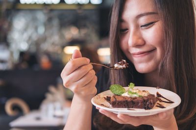 Close-up of smiling young woman having cake in cafe