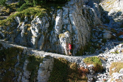 Man walking on trail by rock formation