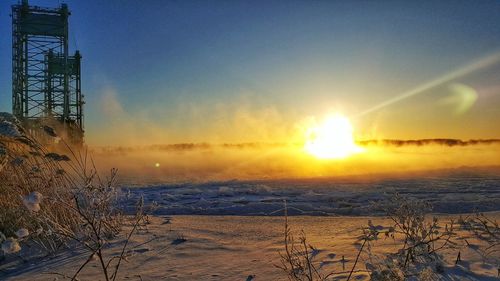 Scenic view of frozen landscape against sky at sunset