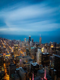 Aerial view of illuminated city buildings against cloudy sky