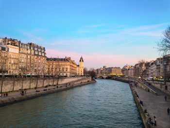 River amidst buildings in city against sky