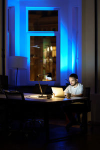 Thoughtful young businessman in glasses work on laptop at night preparing for startup presentation