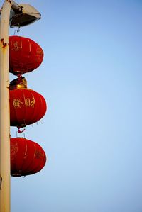 Low angle view of red lanterns hanging from street light against clear sky