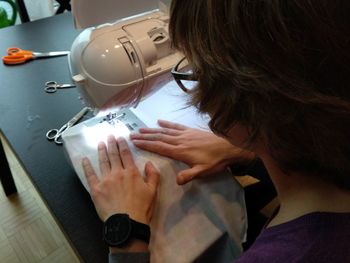 High angle view of mid adult woman stitching on table at home