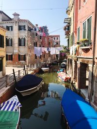 Boats moored in canal amidst buildings in city