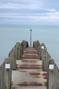 Pier on sea against cloudy sky