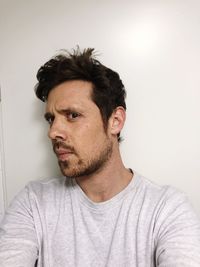 Portrait of young man looking away against white background