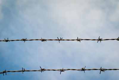 Low angle view of barbed wires against sky