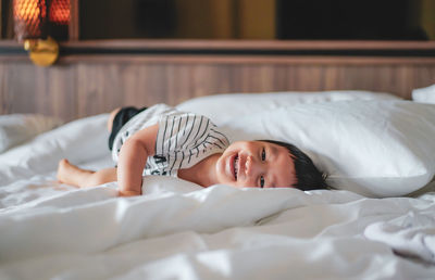 Portrait of little boy wear striped shirt feel relax lying down on bed, looking at camera. bed vibes