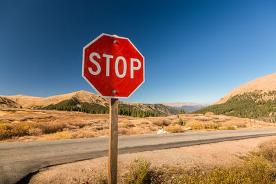 Road sign against clear blue sky