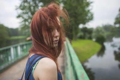 Side view of female traveler standing on old footbridge crossing river and looking at camera while exploring saint petersburg neighborhoods in summer day