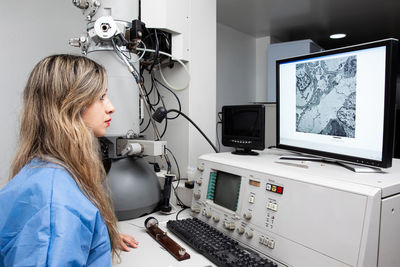 Young female scientist working at the laboratory with an electron microscope