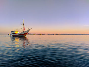 Sailboat sailing in sea against clear sky during sunset