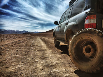 Dirt road on field against sky