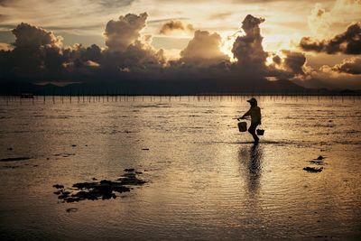 Silhouette man on beach against sky during sunset