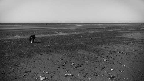 Teenage girl bending at beach against sky