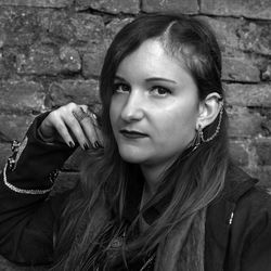 Portrait of young woman standing against brick wall