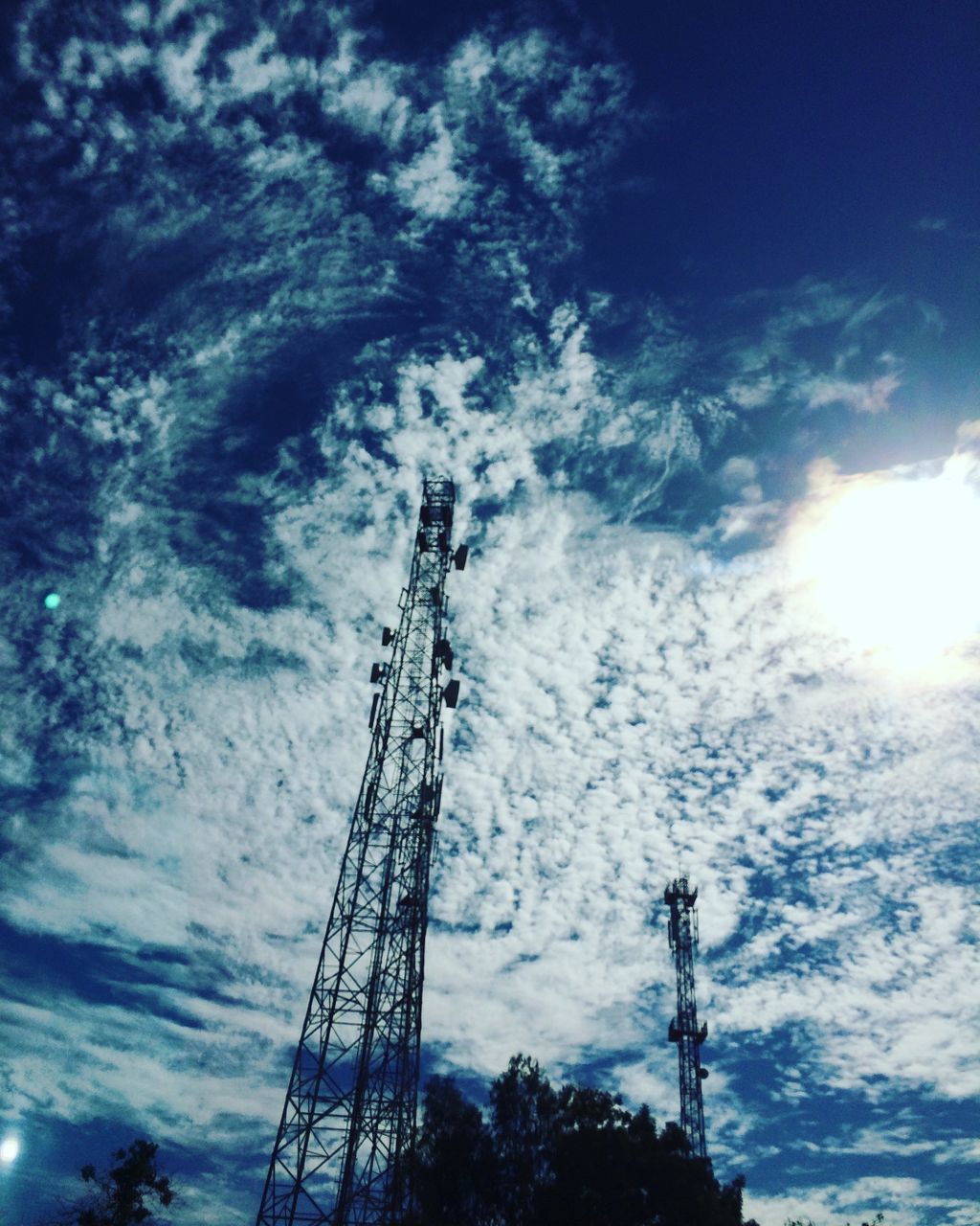 low angle view, sky, cloud - sky, silhouette, cloudy, sunlight, sun, blue, cloud, nature, sunbeam, electricity pylon, electricity, outdoors, fuel and power generation, tall - high, no people, day, technology, power supply