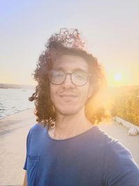 Portrait of mature man on beach against sky during sunset