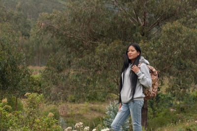 Portrait of young woman standing against trees