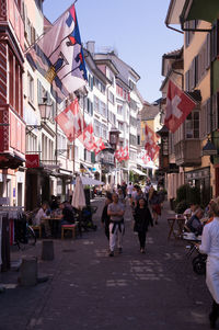 People walking on street amidst buildings in city