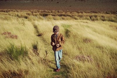 Rear view of woman walking on grassy field