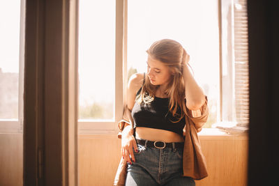 Young woman standing in balcony at home during summer