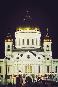 People at illuminated cathedral against sky at night