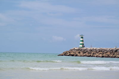 Lighthouse by sea against sky